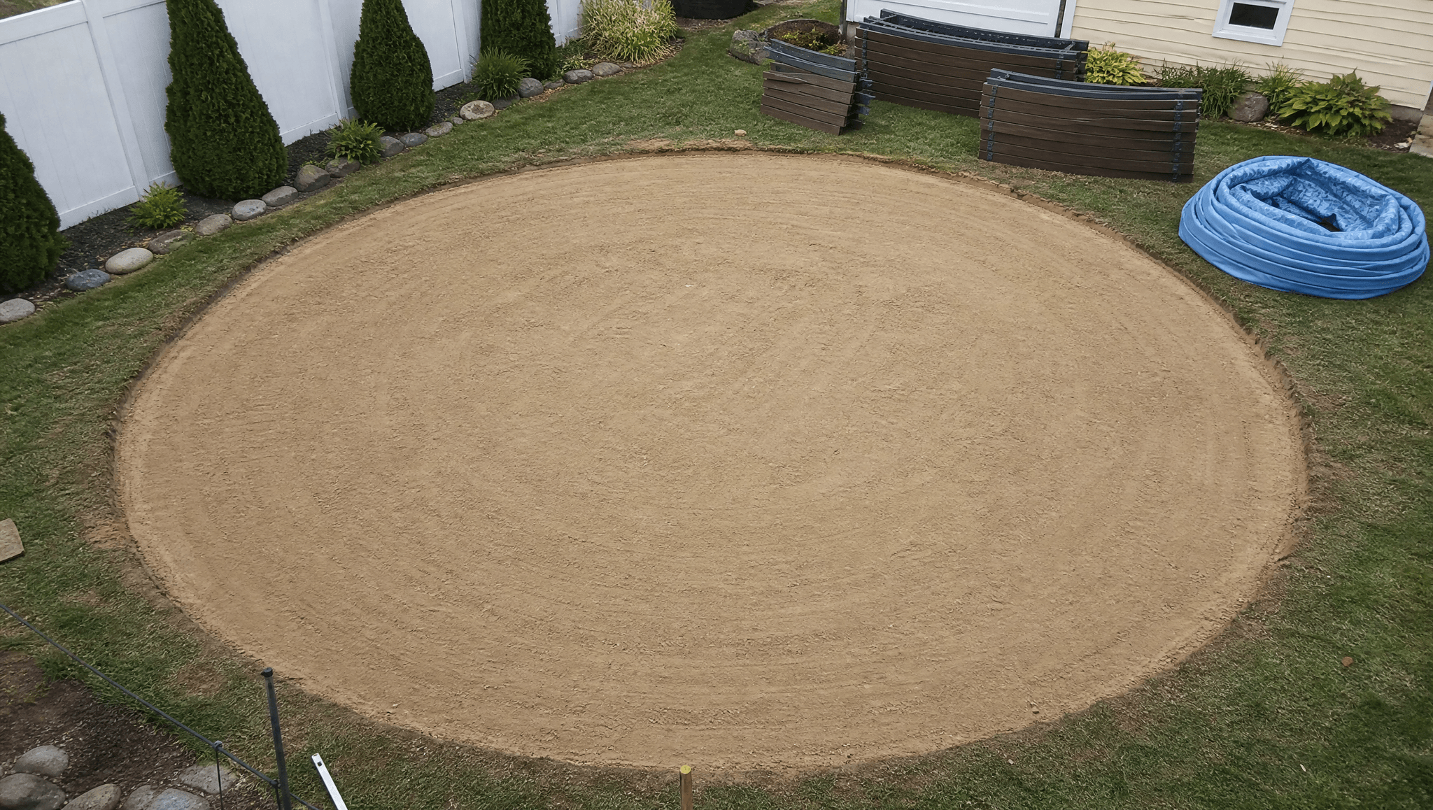 Above-ground pool site prep, leveling sand base in a residential backyard