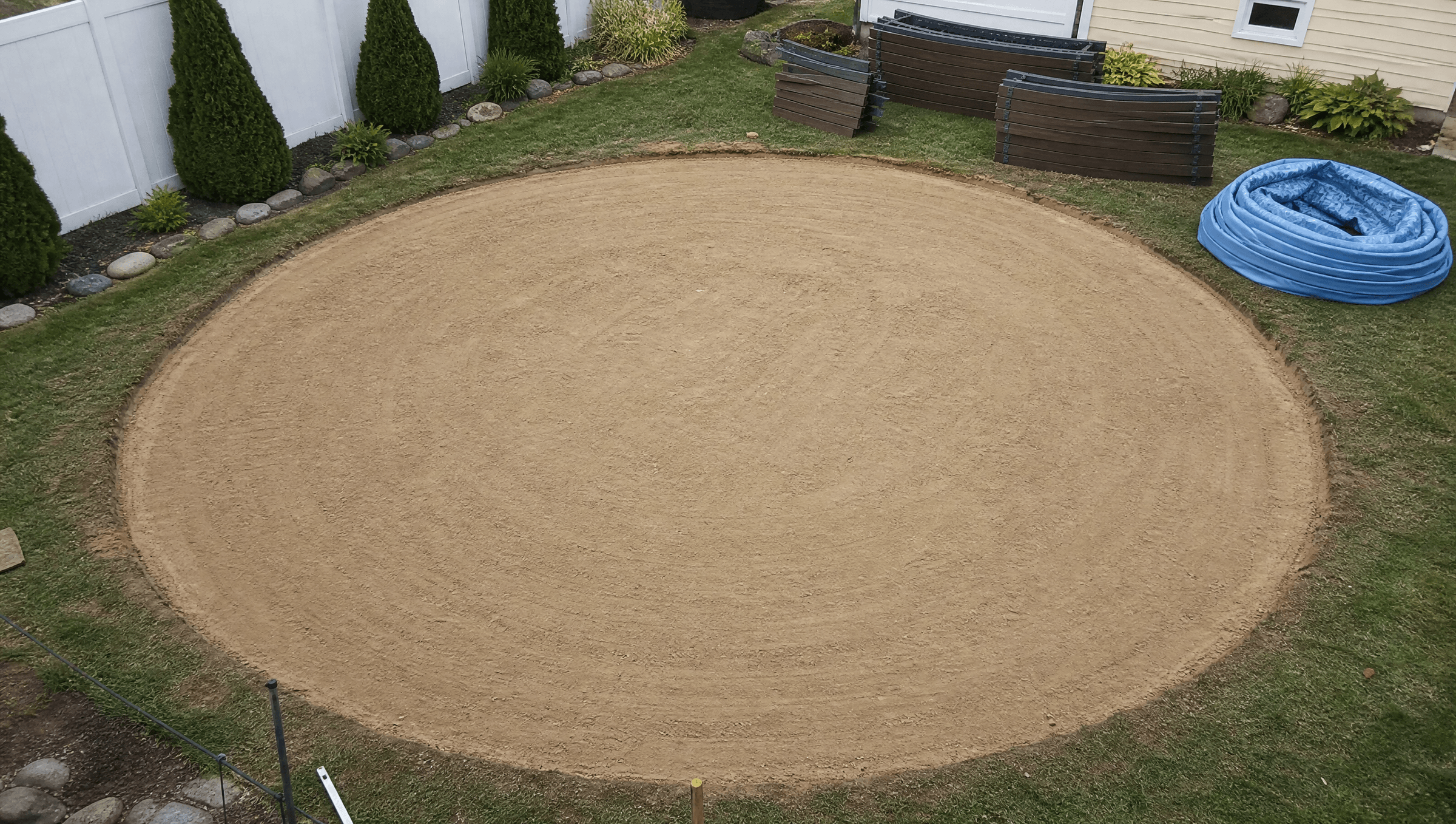 Above-ground pool site prep, leveling sand base in a residential backyard